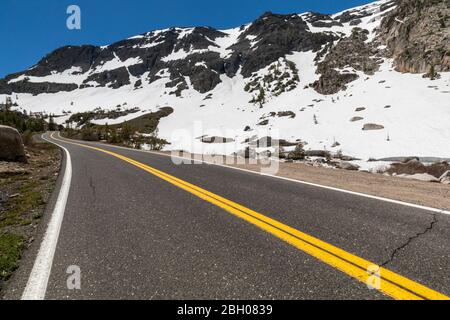 Eine Bergstraße schlängelt sich durch schneebedeckte Berghänge bei Sonora Bestanden Stockfoto