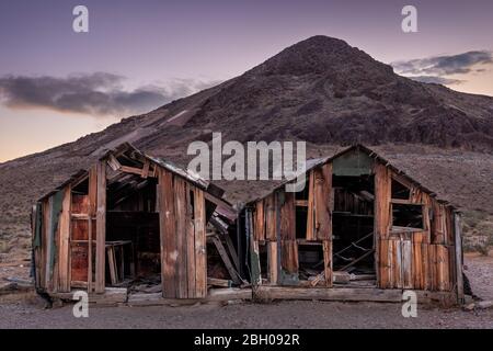 Zwei alte verlassene Blockhütten in der mineralischen Geisterstadt Rhyolite in der Dämmerung Stockfoto