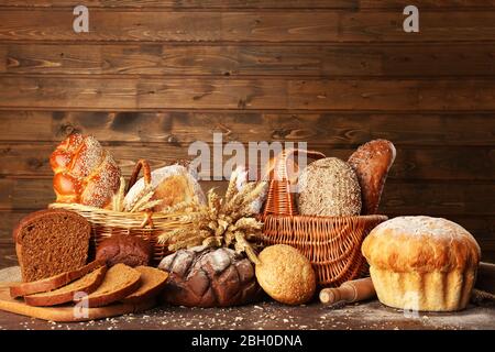Anderes Brot mit Ohren in Korb auf hölzernen Hintergrund Stockfoto