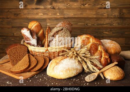 Anderes Brot mit Ohren in Korb auf hölzernen Hintergrund Stockfoto