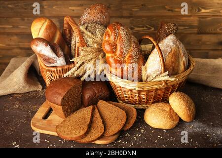 Anderes Brot mit Ohren in Korb auf hölzernen Hintergrund Stockfoto