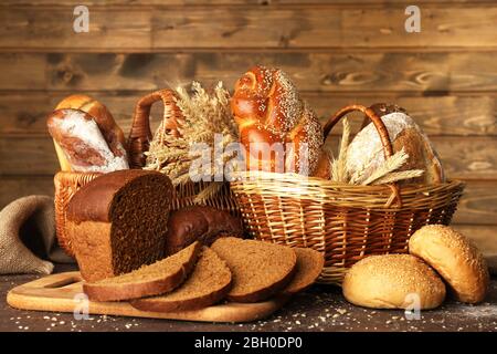 Anderes Brot mit Ohren in Korb auf hölzernen Hintergrund Stockfoto