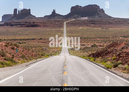 Eine einsame Straße erstreckt sich bis zum ikonischen Mesas des Monument Valley Stockfoto