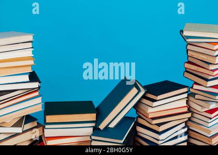 Eine Menge Stapel von Lehrbüchern in der Hochschulbibliothek auf einem blauen Hintergrund Stockfoto