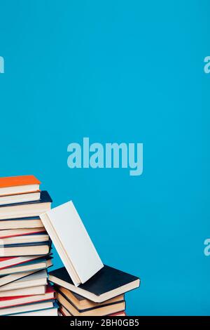 Eine Menge Stapel von Lehrbüchern in der Hochschulbibliothek auf einem blauen Hintergrund Stockfoto