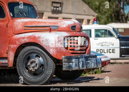 Nahaufnahme eines roten Vintage-Abschleppwagens mit einem Oldtimer-Polizeiauto im Hintergrund Stockfoto