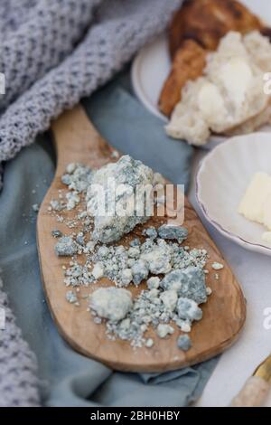 Vertikales Bild von blauem Lammkäse auf einem hölzernen Olivenbrett mit Butter und Brot serviert platziert. Stockfoto