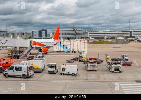 Schwere Wolken über dem Flugplatz. Viele Hilfseinrichtungen. Passagiere steigen entlang der Rampe auf das Flugzeug Stockfoto
