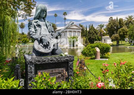 Nahaufnahme Johnny Ramone Bronze Grabstein in Hollywood Forever, porträtiert ihn spielen eine Gitarre, mit Vegetation im Hintergrund Stockfoto