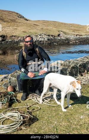 Hildasay, Shetland, Schottland, Großbritannien, 22. April 2020, Ex-Fallschirmjäger und Wohltätigkeitswanderer Chris Lewis und sein Begleiter Jet auf der Insel Hildasay an der Westküste von Shetland, wo sie sich während der COVID-19 Pandemie selbst isolieren. Chris ist auf einem wohltätigen Spaziergang um die Küste von Großbritannien, die er begann im Jahr 2017. Das gesamte Geld geht an die SSAFA-Wohltätigkeitsorganisation. Die Insel Hildasay ist eine unbewohnte Insel und Chris und Jet sind die einzigen Bewohner während dieser Zeit. Foto: Dave Donaldson Credit: Dave Donaldson/Alamy Live News Stockfoto