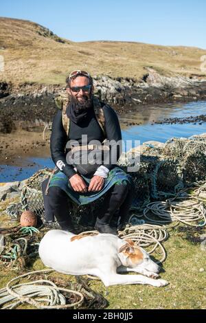 Hildasay, Shetland, Schottland, Großbritannien, 22. April 2020, Ex-Fallschirmjäger und Wohltätigkeitswanderer Chris Lewis und sein Begleiter Jet auf der Insel Hildasay an der Westküste von Shetland, wo sie sich während der COVID-19 Pandemie selbst isolieren. Chris ist auf einem wohltätigen Spaziergang um die Küste von Großbritannien, die er begann im Jahr 2017. Das gesamte Geld geht an die SSAFA-Wohltätigkeitsorganisation. Die Insel Hildasay ist eine unbewohnte Insel und Chris und Jet sind die einzigen Bewohner während dieser Zeit. Foto: Dave Donaldson Credit: Dave Donaldson/Alamy Live News Stockfoto