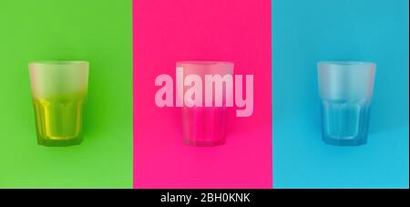 Angeordnet leere transparente mehrfarbige Trinkgläser auf bunten Hintergrund minimalistischen Kopieraum Stockfoto