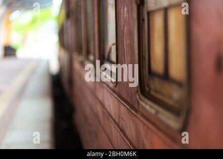 Leerer Bahnsteig eines Bahnhofs in Sri Lanka. Alte rostige Zugwagen. Es sieht aus wie ein verlassene Ort, aber es ist nicht. Stockfoto