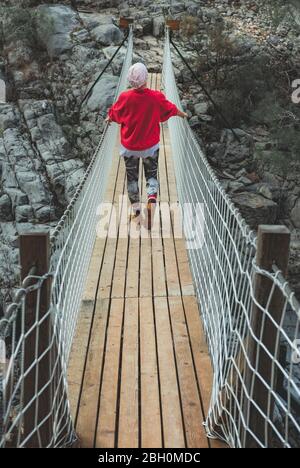 Erwachsene Frau auf einer hängenden Holzbrücke in der Natur. Wandererin in Goynuk Kanyonu in Antalya, Türkei. Stockfoto