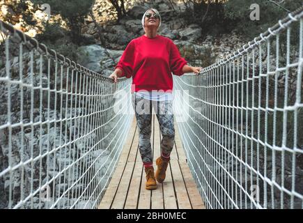 Erwachsene Frau auf einer hängenden Holzbrücke in der Natur. Wandererin in Goynuk Kanyonu in Antalya, Türkei. Stockfoto