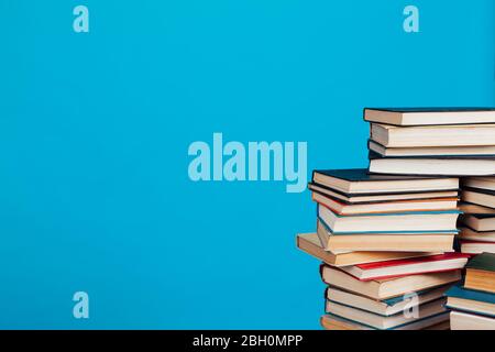 Eine Menge Stapel von Lehrbüchern in der Hochschulbibliothek auf einem blauen Hintergrund Stockfoto