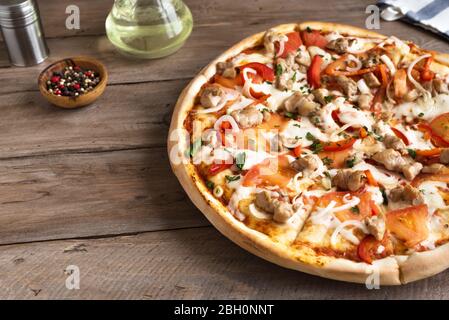Frische Grill-Chicken-Pizza mit Gemüse und Mozzarella-Käse auf Holztisch. BBQ Pizza mit Hühnerstücken. Stockfoto