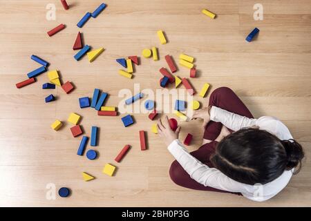 Draufsicht auf ein unbekanntes kleines Mädchen zu Hause mit Bausteinen spielen, Konzept der Indoor-Freizeit für Kinder Stockfoto