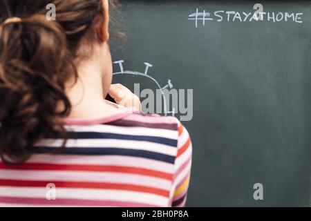 Kind, das einen Coronavirus auf eine Tafel mit der Nachricht zeichnet, zu Hause bleiben, Konzept der Kinder in Quarantäne, kopieren Raum für Text Stockfoto