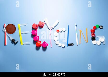 Das Wort Recycling mit verschiedenen Kunststoff-Müll-Elemente auf bunten Hintergrund zusammengesetzt Stockfoto