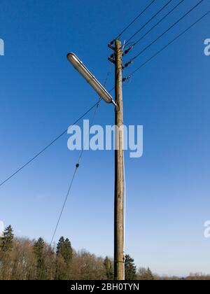 Straßenlampe und Telefonmast aus Holz mit Kabeln und Leitungen gegen klaren blauen Himmel in der Landschaft in Rheinland-Pfalz, Deutschland, Westeuropa Stockfoto