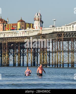 Brighton UK 23. April 2020 - Frühmorgendliche Schwimmer genießen ein Bad im Meer am Brighton Palace Pier an einem schönen heißen sonnigen Tag während der Sperrbeschränkungen während der Coronavirus COVID-19 Pandemie Krise . Die Temperaturen werden voraussichtlich 25 Grad in einigen Teilen des Südostens heute zu erreichen. Quelle: Simon Dack / Alamy Live News Stockfoto