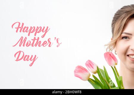 Happy Mother's Day rosa Text Zeichen und ein halbes Gesicht der jungen Frau mit Bouquet von Frühling rosa Tulpen auf weißem Hintergrund. Stockfoto