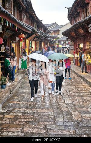 Lijiang, China - 22. September 2017: Menschen auf der Straße der Altstadt an einem regnerischen Tag. Die Altstadt von Lijiang wurde in die UNESCO-Welt Kulturelle He aufgenommen Stockfoto