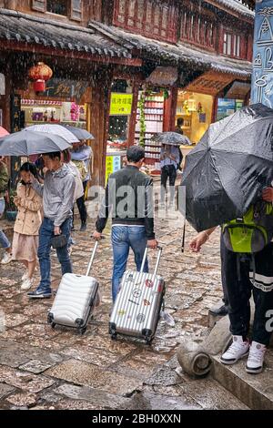 Lijiang, China - 22. September 2017: Touristen auf der Straße der Altstadt an einem regnerischen Tag. Die Altstadt von Lijiang wurde in die UNESCO-Weltkultur aufgenommen Stockfoto