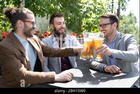 Fröhliche junge Geschäftsleute unterhalten sich und trinken Bier in einer Kneipe Stockfoto