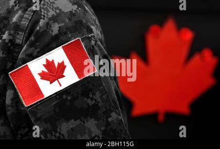 Canada Day. Flagge von Kanada auf der Uniform und Red Maple Leaf auf dem Hintergrund. Kanadische Soldaten. Armee von Kanada. Kanada Blatt. Erinnerung D Stockfoto