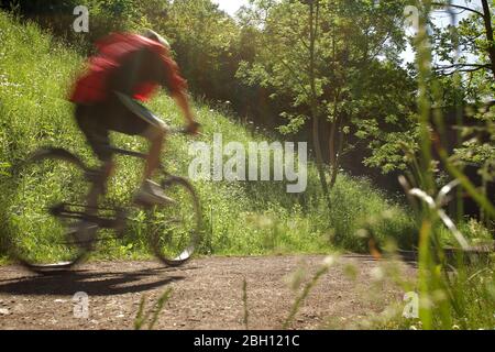 Motion-Foto eines Radfahrers, der an einem sonnigen Tag auf einer Strecke auf dem Land fährt Stockfoto