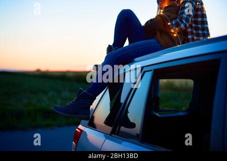 Liebevolles Paar umarmen und sitzen auf dem Auto Stockfoto