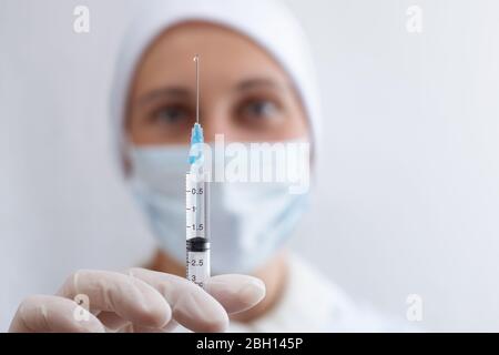 Eine Krankenschwester hält eine Spritze mit Medikamenten auf Augenhöhe. Der Arzt überprüft die Füllung der Spritze. Stockfoto