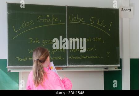 Hannover, Deutschland. April 2020. Eine Schülerin einer 5. Klasse steht vor einer Tafel im Gymnasium Tellkampfschule mit der Mitteilung, dass sie ihr Arbeitsmaterial mit nach Hause nehmen sollte. In Niedersachsen sind die Schulen seit Mitte März aufgrund der Corona-Pandemie geschlossen. Ab dem 4. Mai sollen die Klassen Schritt für Schritt wieder in die Schulen zurückkehren. Bis dahin sollen die Schüler zu Hause lernen und Online-Unterricht erhalten. Kredit: Julian Stratenschulte/dpa/Alamy Live News Stockfoto
