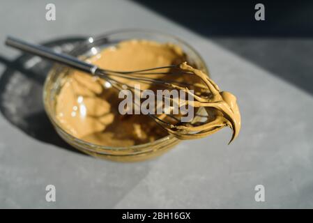 Schlagen Sie Instant-Kaffee für dalgona Getränk mit Schneebesen. Hartes Sonnenlicht, Betonhintergrund Stockfoto