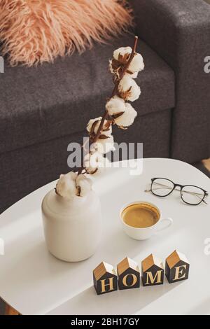 Baumwollzweige in einer Vase auf einem kleinen Tisch im Wohnzimmer. Stockfoto
