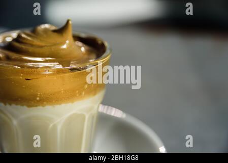 Dalgona Instant-Kaffee Schlagsahne Getränk in Glas. Hartes Sonnenlicht, Betonhintergrund. Nahaufnahme der Oberfläche. Stockfoto