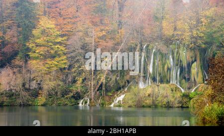 Kleine Wasserfälle umgeben von Bäumen mit schönen Herbstfarben im Nationalpark Plitvicer Seen, Kroatien Stockfoto