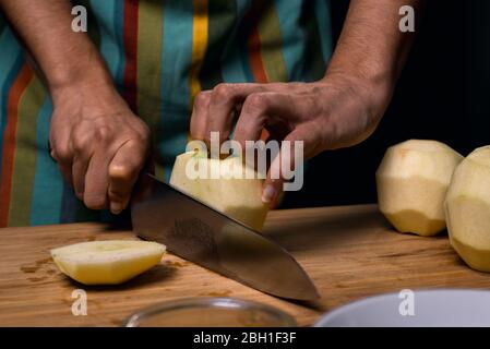 Arbeiten in der Küche. Detail der Hände schneiden Apfel in Stücke. Schneidebrett. Kochmesser. Stockfoto