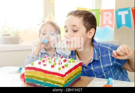 Schöne Kinder feiern Geburtstag und blasen Kerzen auf Kuchen Stockfoto