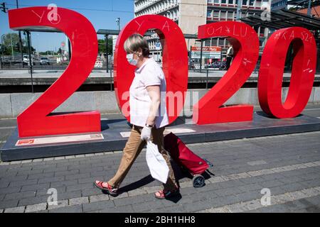 Köln, Deutschland. April 2020. Eine Frau mit Schutzmaske geht am Wiener Platz an dem Jahr 2020 vorbei. Das öffentliche Leben wird durch die Coronavirus-Krise weiter eingeschränkt. Quelle: Federico Gambarini/dpa/Alamy Live News Stockfoto