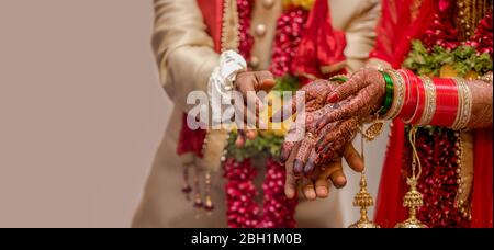 Sehr schönes Foto von neu verheirateten indischen Paar in ethnischer Kleidung, die Blumen zu Gott und den Segen. Brauthände mit Armreifen verziert. Stockfoto