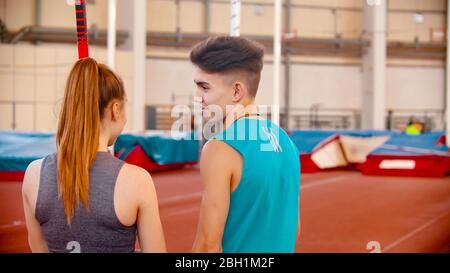 Pole Vault - junger Mann und Frau stehen auf dem Stadion und Blick auf andere Sportler Ausbildung. Mittelaufnahme Stockfoto