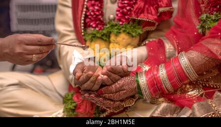 Traditionelle indische Hochzeitsszene, in der ein schönes Paar an hinduistischen Ritualen ihrer Trauung teilnimmt. Das Paar empfängt heiliges Wasser. Stockfoto