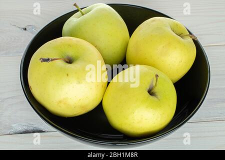Gruppe von vier ganzen grünen köstlichen Apfel in Schüssel auf weißem Holz Stockfoto