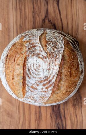 Ein Laib Sauerteigbrot auf einem hölzernen Brottafel fotografiert von oben. Stockfoto