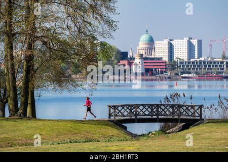 Potsdam, Deutschland. April 2020. Am Morgen joggte eine Frau durch den Glienicker Park am Ufer des Tiefsees vor der Kulisse der Nikolaikirche und der Häuser im Zentrum von Potsdam. Quelle: Soeren stache/dpa-Zentralbild/ZB/dpa/Alamy Live News Stockfoto