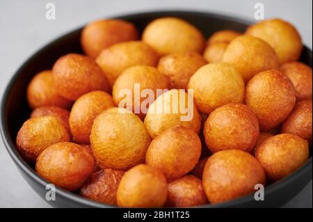 Loukoumades oder luqaimat oder Lokma in schwarzer Schüssel. Loukoumades ist eine östliche Küche Donunts beliebt während Ramazan. Beliebte Ramadan-Gerichte. Iftar und Suhu Stockfoto