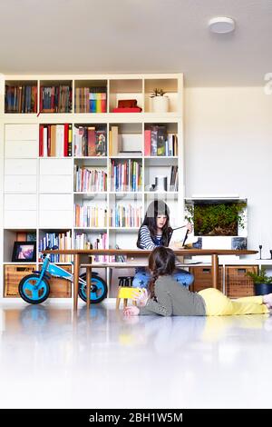 Schwestern, die zu Hause elektronische Geräte benutzen Stockfoto